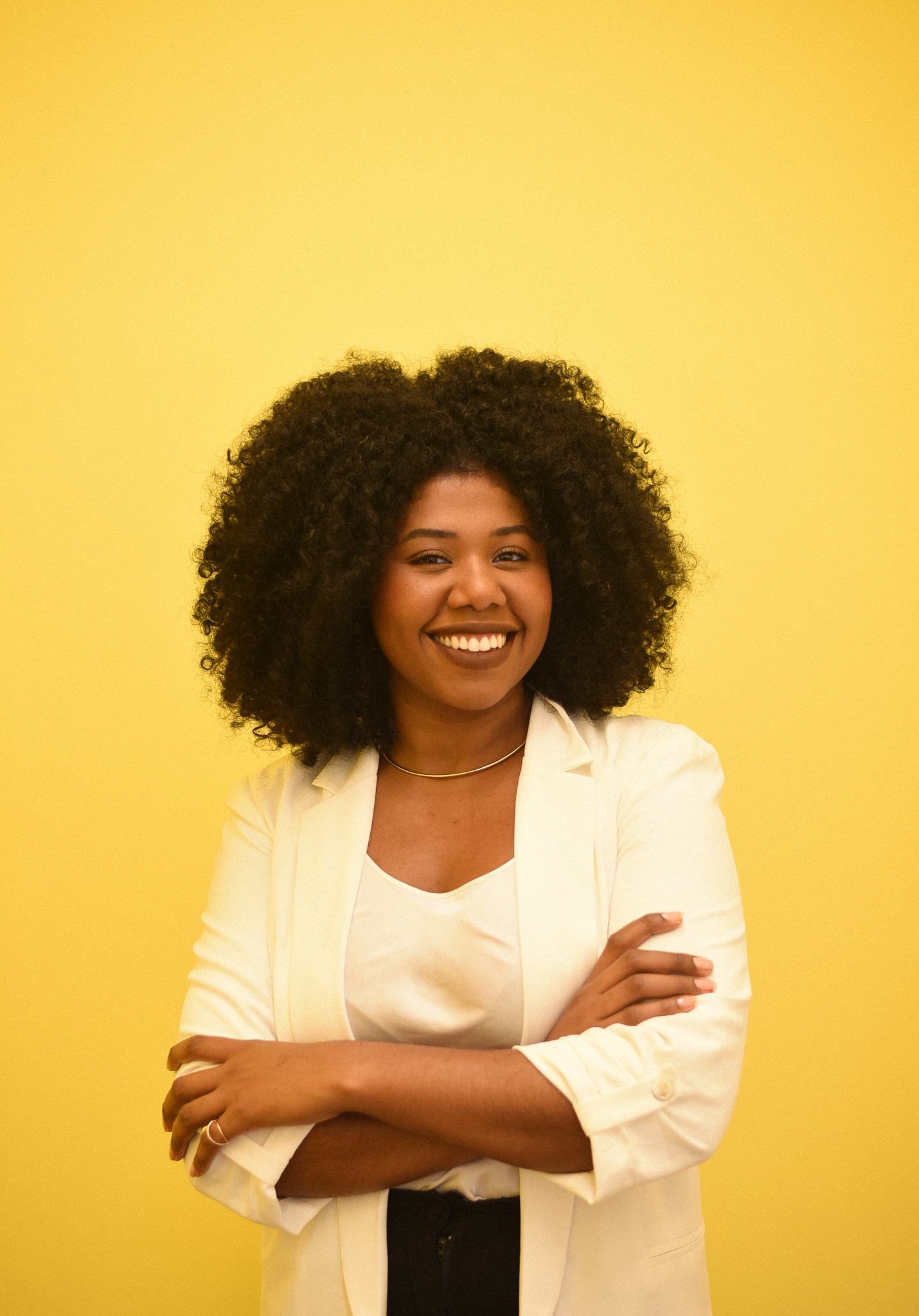Dina Prates, fundadora da Ujamaatech, sorrindo de braços cruzados